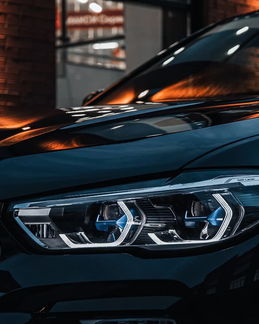 A lit headlight on a dark SUV at night
